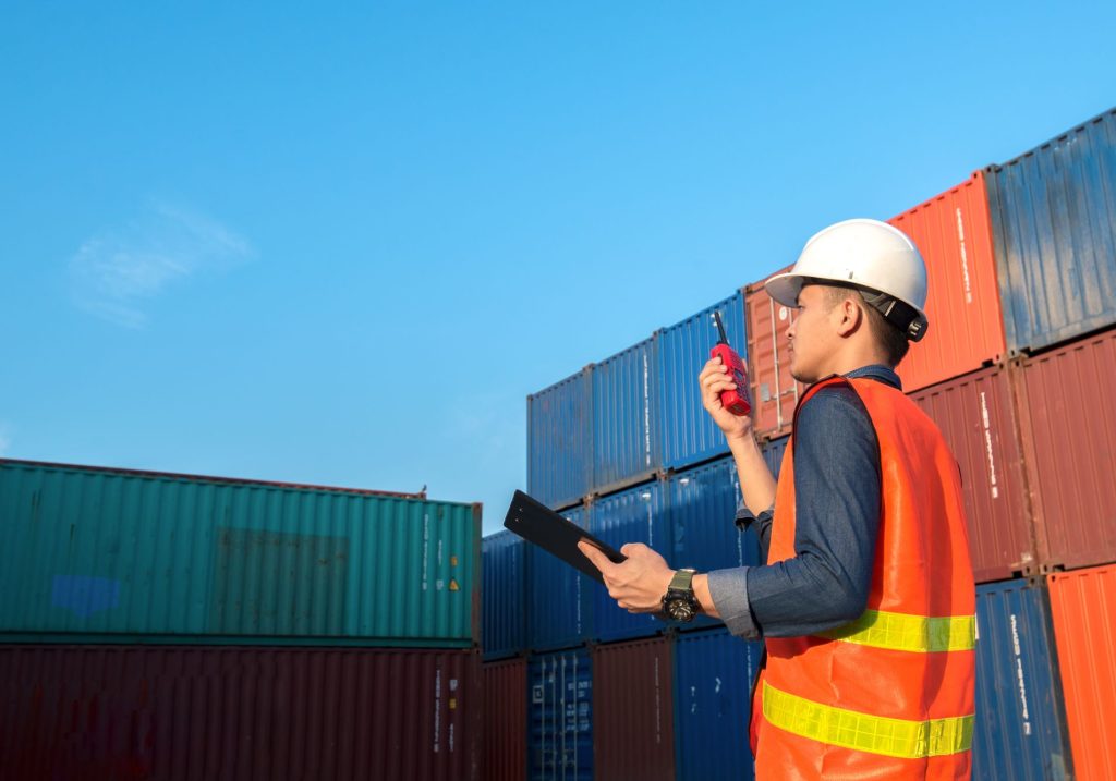 A man in an orange vest holding a clipboard, possibly conducting an inspection or survey.